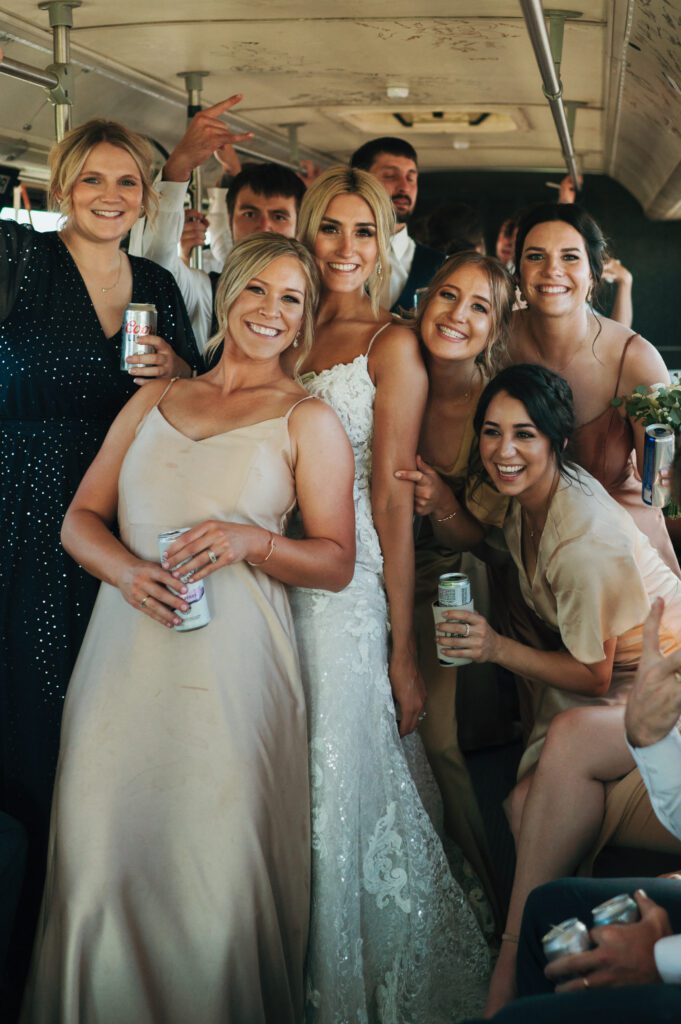 bride and all her friends group together and smile on party bus
