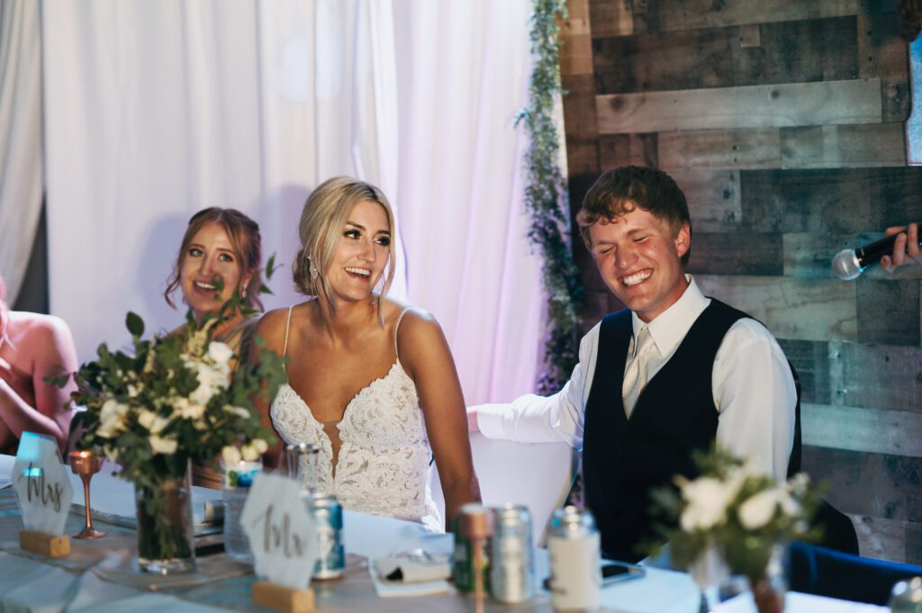 bride laughs during speeches at their wedding reception
