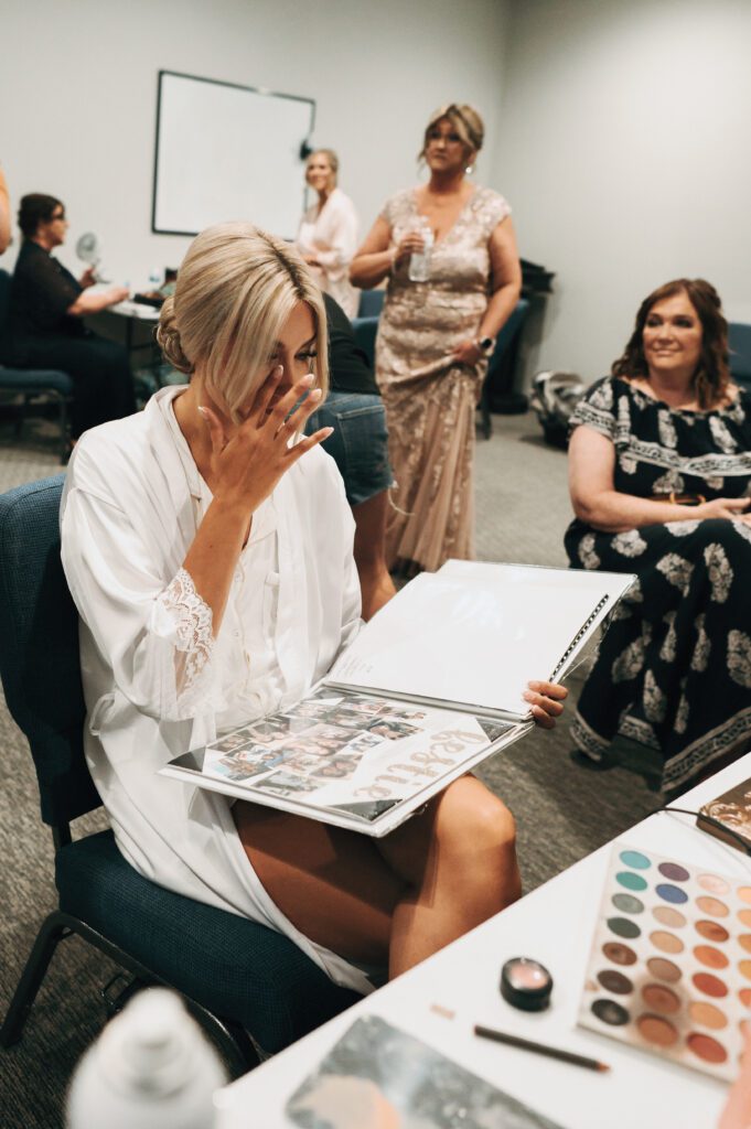 bride wipes away tear as she looks through photos of her friends
