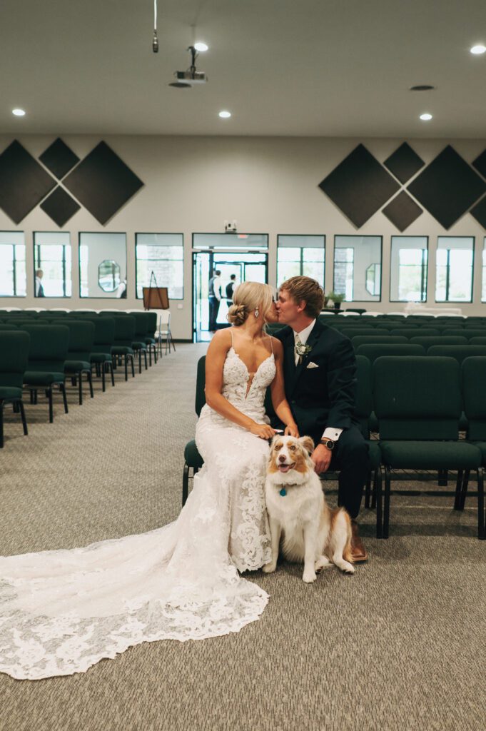 bride and groom kiss with their dog between them