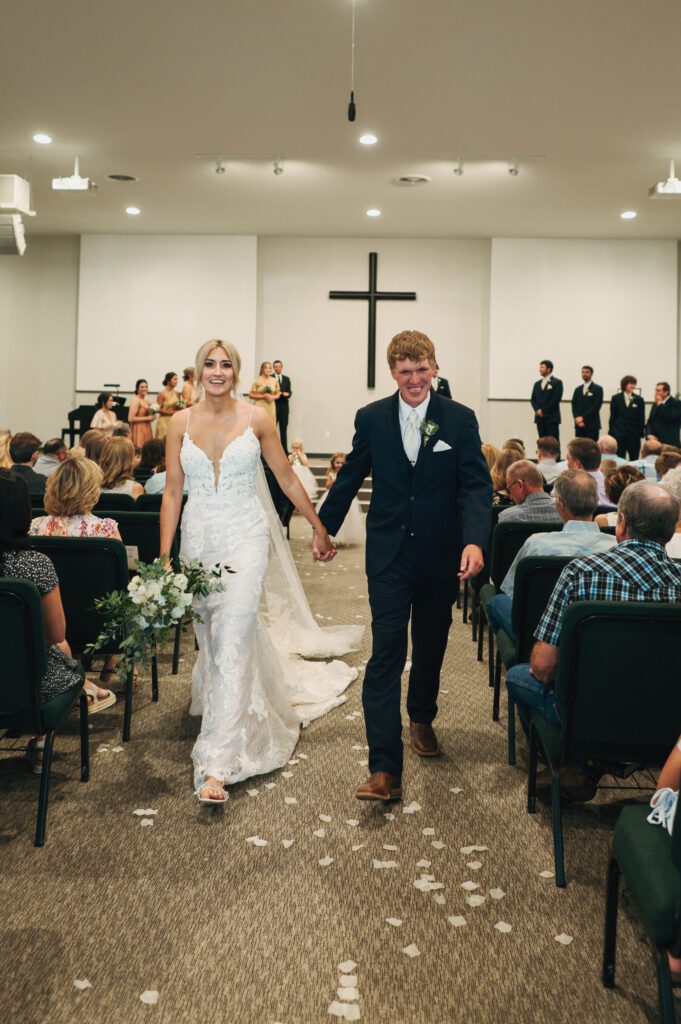 bride and groom smile as they walk down the aisle after getting married in Kansas