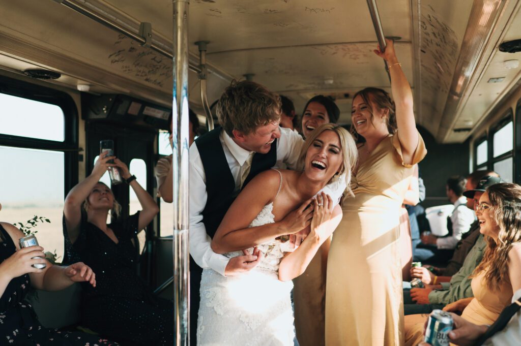 groom wraps arm around bride in party bus as they laugh together