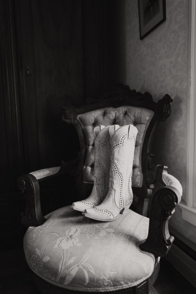 black and white wedding photo of cowgirl boots sitting on chair
