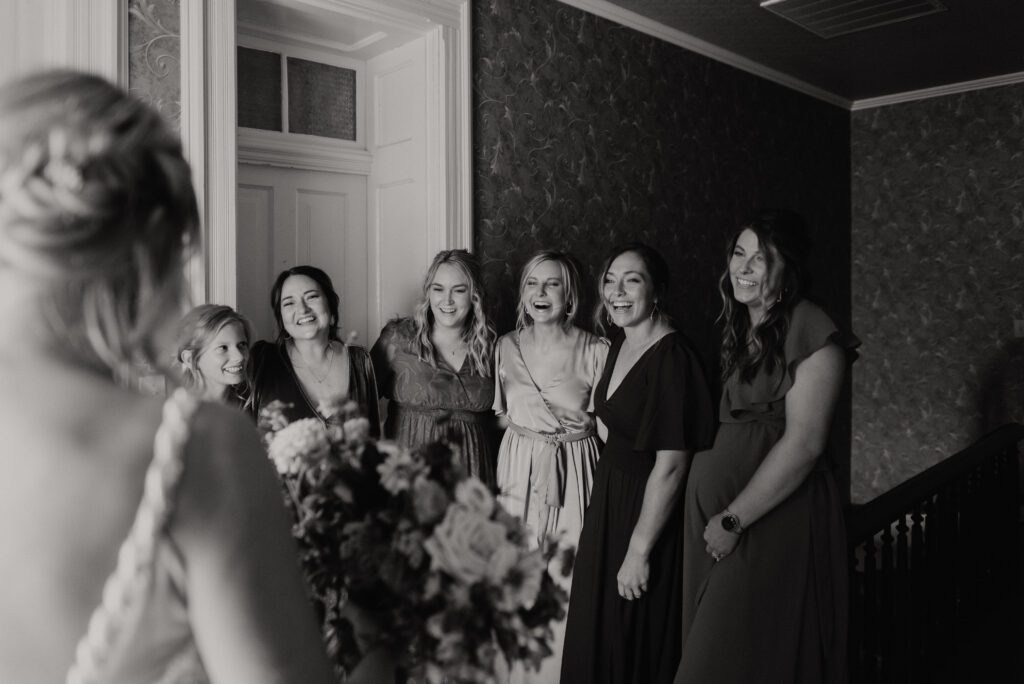 black and white wedding photo of six bridesmaids smiling at bride