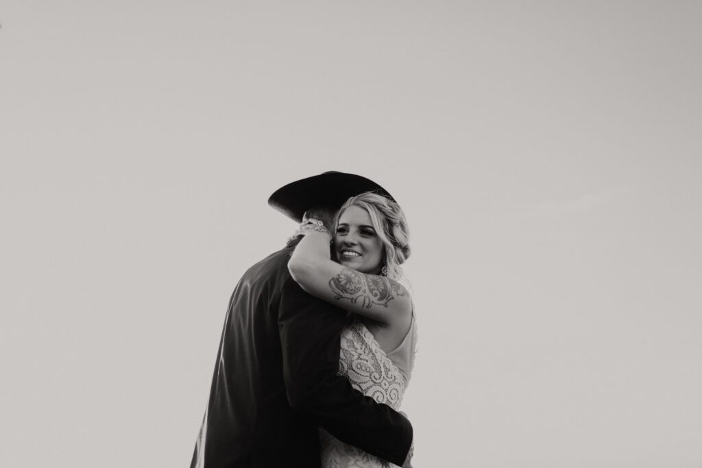 black and white wedding photo of bride and groom dancing at sunset