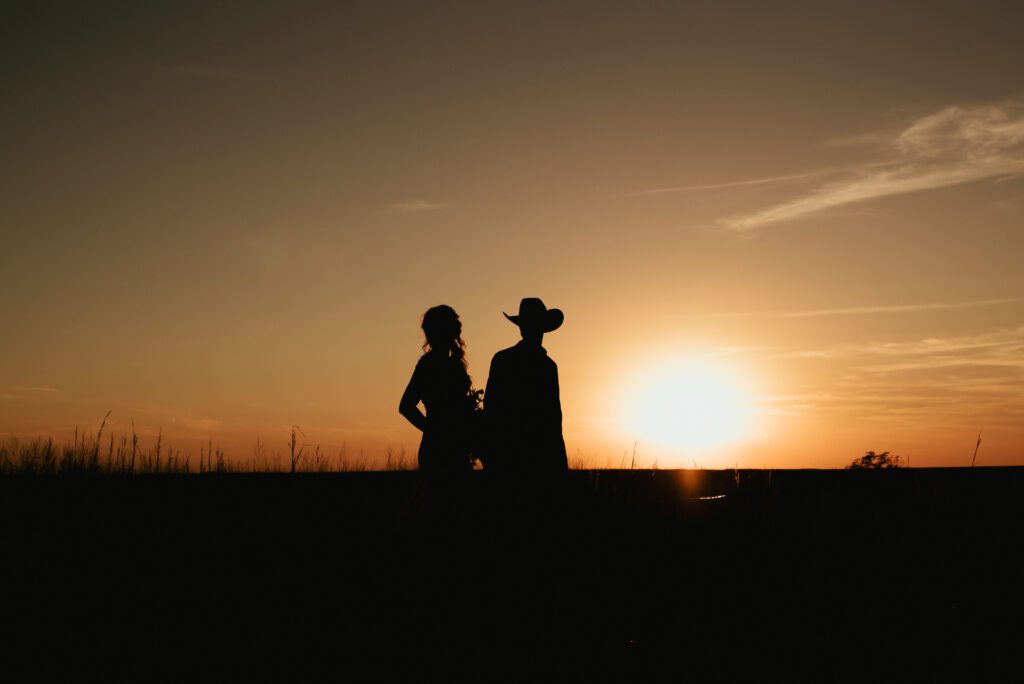 silhouette of bride and groom in cowboy hat walking at clover cliff ranch